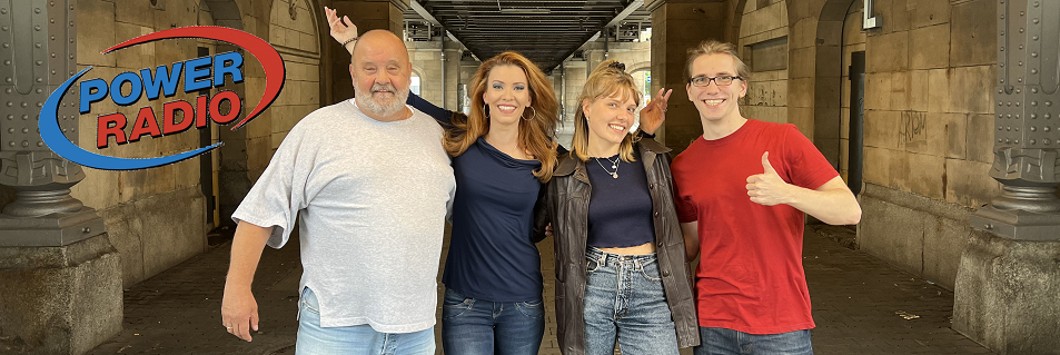 Vier Mitglieder des Power-Radio-Teams mit dem Senderlogo vor einer Brücke